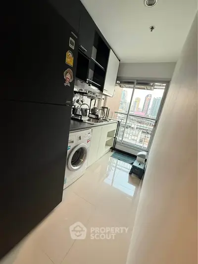 Modern kitchen with sleek black cabinets and city view balcony, featuring washing machine and appliances.