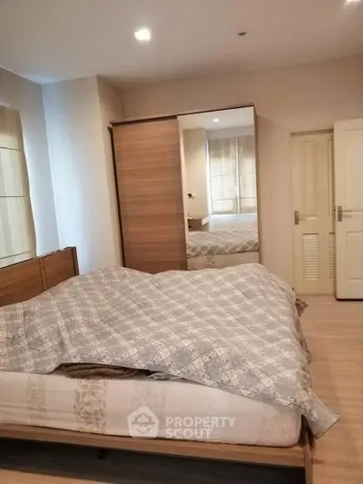 Cozy bedroom with wooden wardrobe and soft lighting, perfect for relaxation.