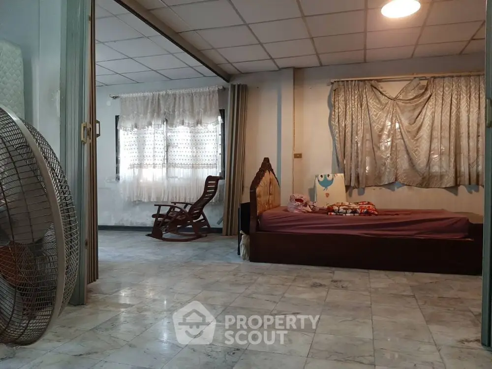 Spacious bedroom with marble flooring and natural light, featuring a cozy bed and rocking chair.