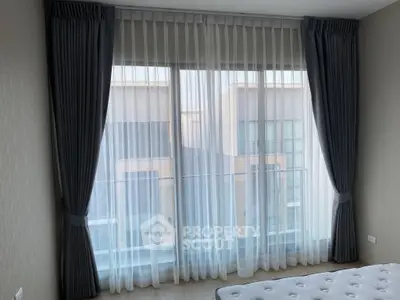 Spacious bedroom with large window and elegant curtains offering a serene view.