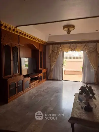 Elegant living room with classic wooden furniture and large windows opening to a patio.