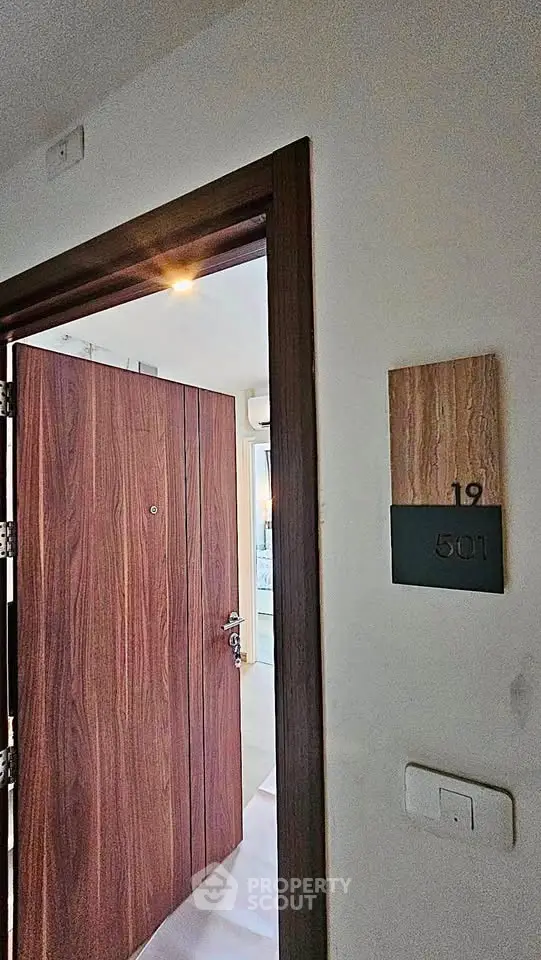 Modern apartment entrance with wooden door and room number 501, showcasing sleek design.