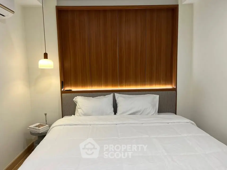 Cozy bedroom with modern lighting and wooden accents, perfect for relaxation.