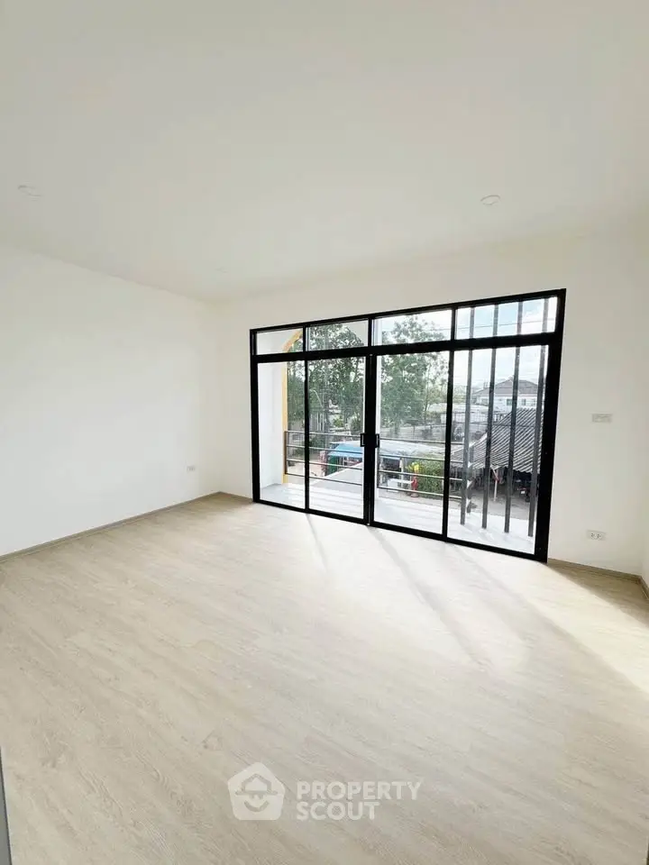 Spacious empty room with large windows and wooden flooring, offering a bright and airy atmosphere.