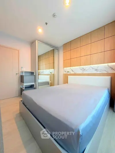 Modern bedroom with sleek design, featuring a large mirror and stylish wooden accents.
