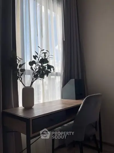 Cozy study nook with desk, chair, and natural light through window curtains.