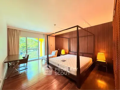 Spacious bedroom with elegant wooden flooring and large windows for natural light.