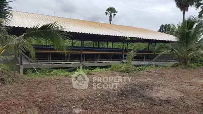 Spacious agricultural structure with metal roof in lush rural setting, ideal for farming or storage.