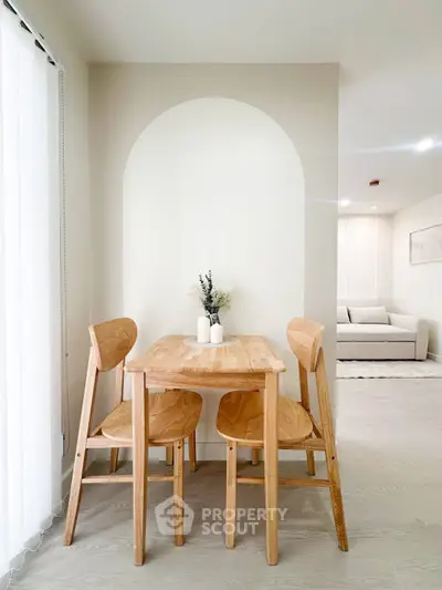 Modern dining area with wooden table and chairs in a bright, minimalist apartment.