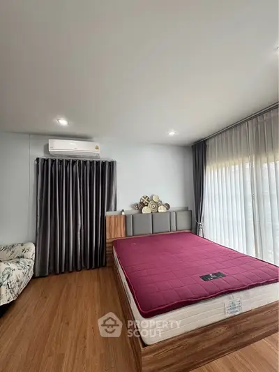 Spacious bedroom with modern decor and large windows for natural light