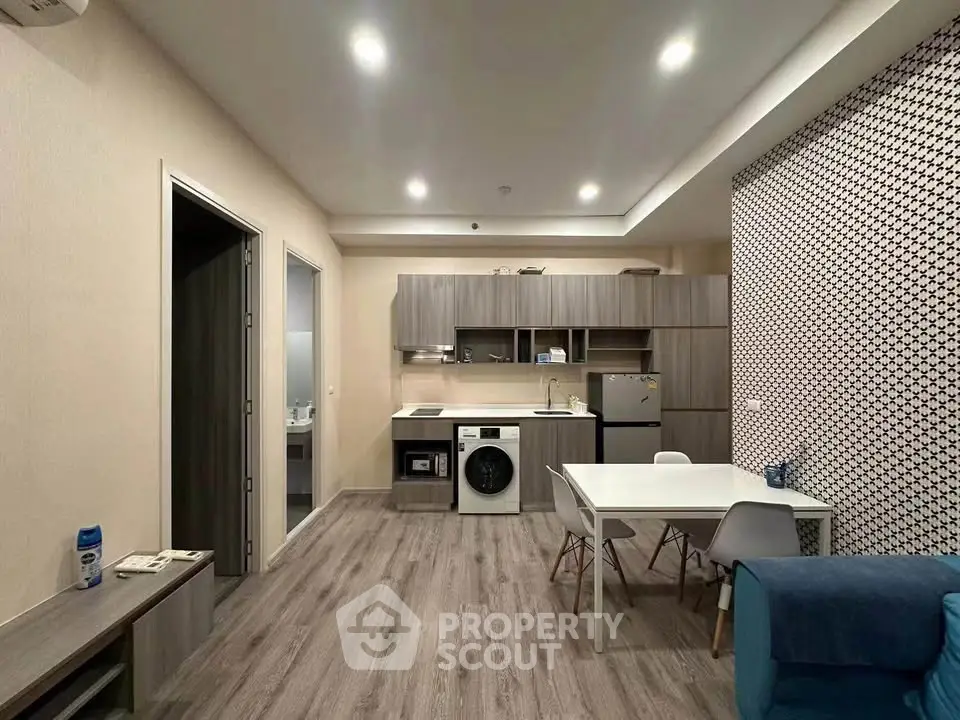 Modern open-plan living room with kitchen, featuring sleek appliances and stylish decor.
