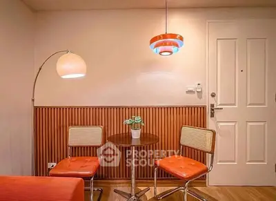 Charming retro-style living room with vibrant orange chairs and stylish lighting.
