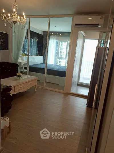 Luxurious modern living room with elegant chandelier and glass partition leading to bedroom.