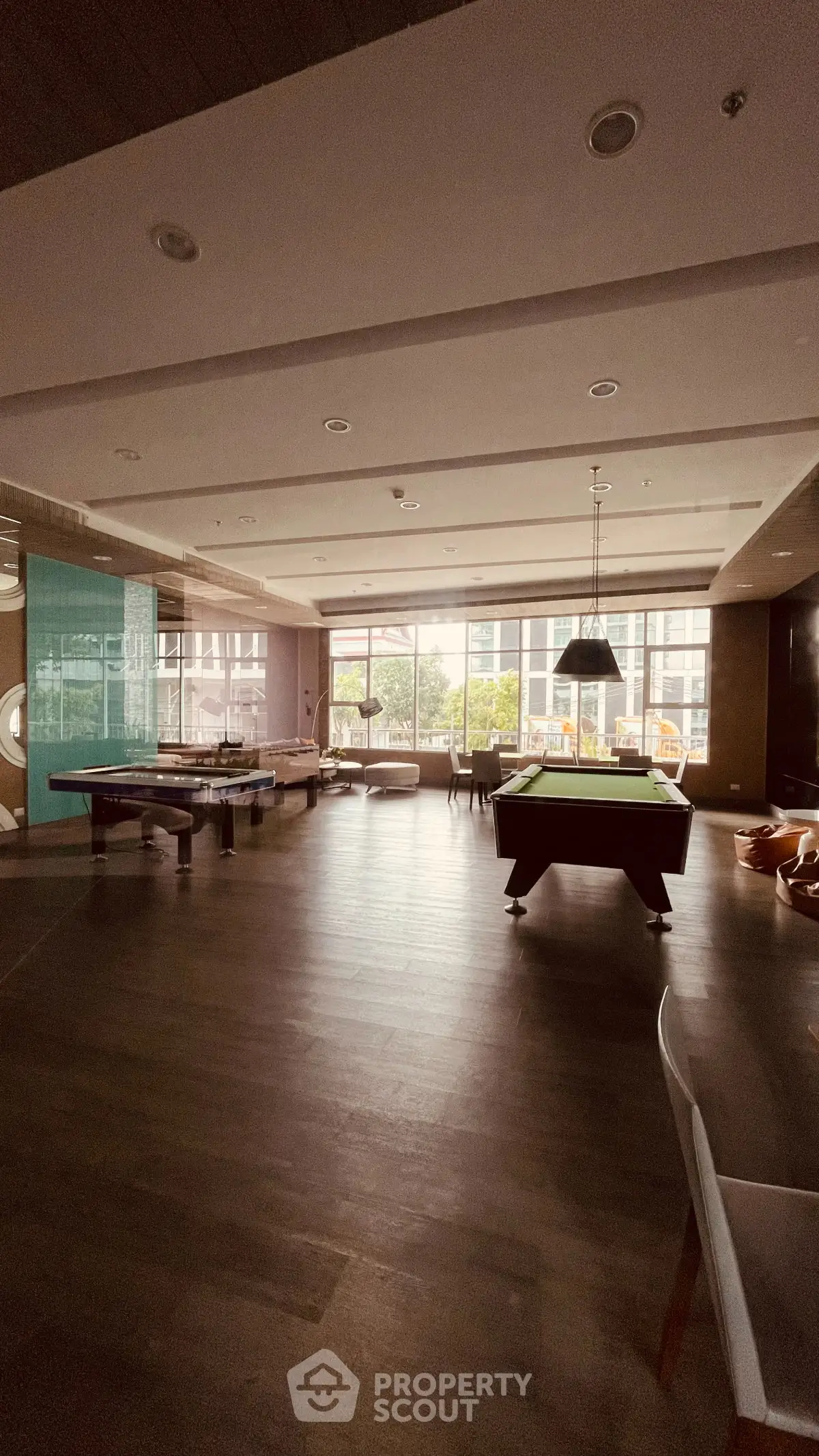 Spacious recreation room with pool tables and large windows in modern building.