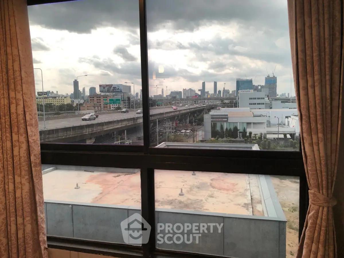 Stunning cityscape view from a high-rise apartment window, showcasing urban skyline and highway.