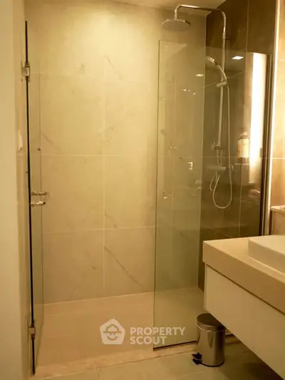 Modern bathroom with glass shower enclosure and sleek vanity in contemporary apartment.