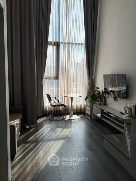 Modern living room with high ceilings and large windows, featuring stylish furniture and abundant natural light.