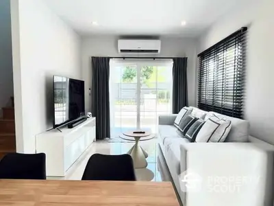 Modern living room with large window, sleek furniture, and air conditioning unit.