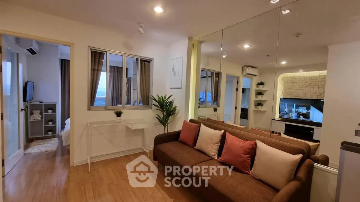 Modern living room with cozy sofa, mirrored wall, and open kitchen layout in stylish apartment.