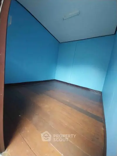 Compact room with blue walls and wooden flooring, ideal for storage or small office space.