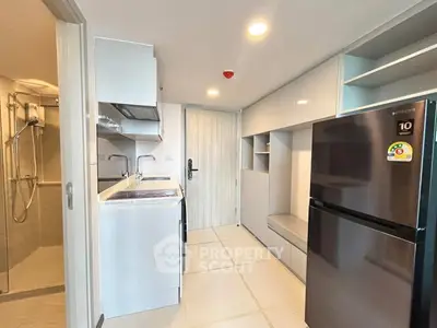 Modern kitchen with sleek appliances and adjacent bathroom in compact apartment.