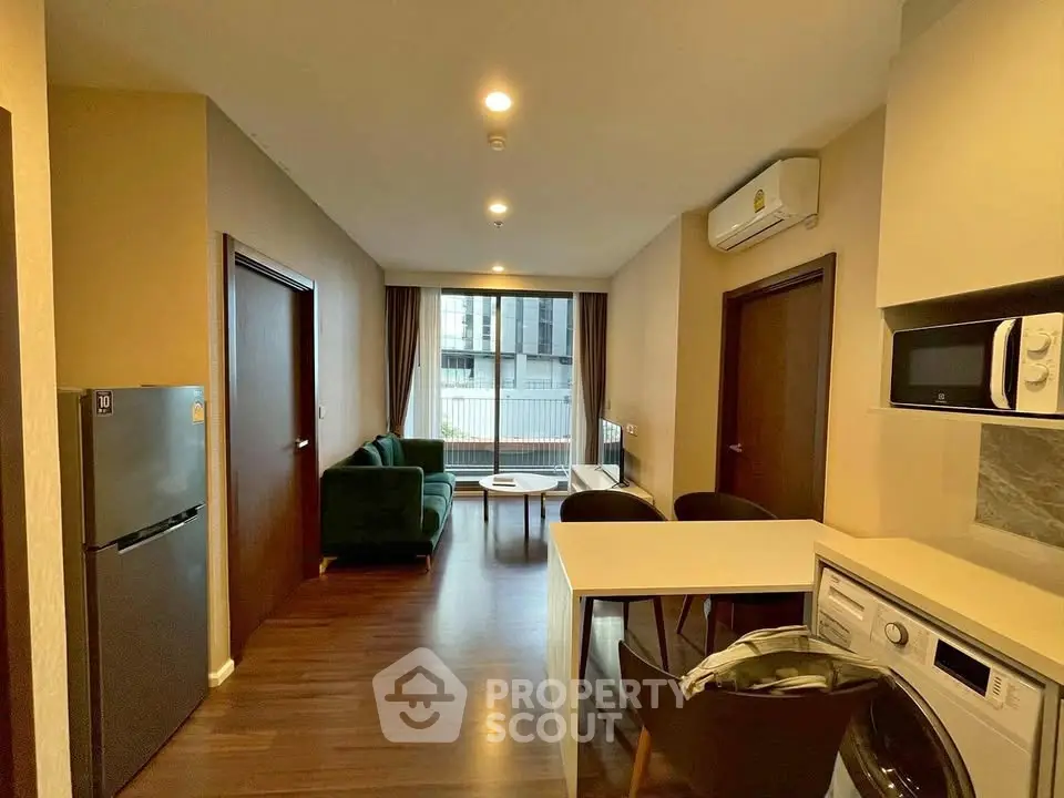 Modern open-plan living room with kitchen, featuring washing machine and stylish decor.