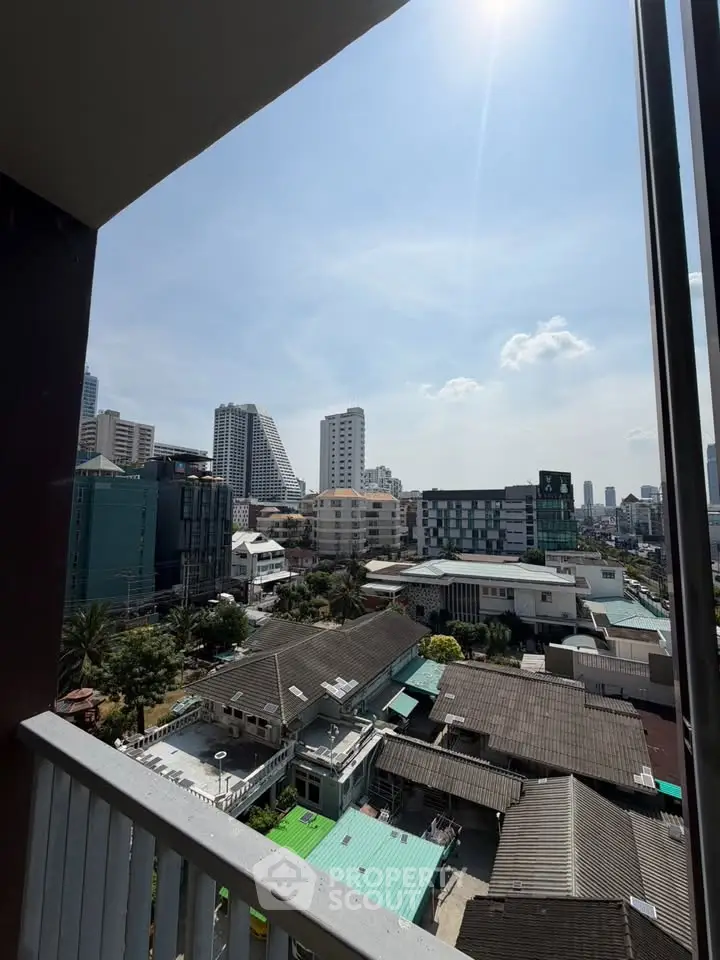 Stunning cityscape view from a high-rise balcony showcasing urban skyline and clear blue sky.