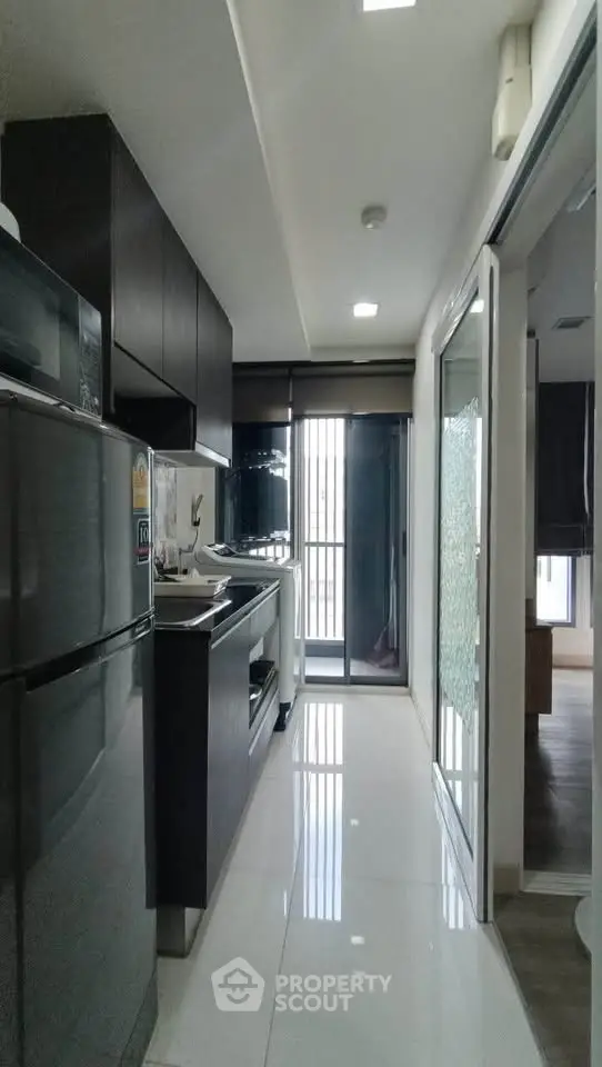 Modern kitchen with sleek appliances and glossy cabinets in a compact layout.