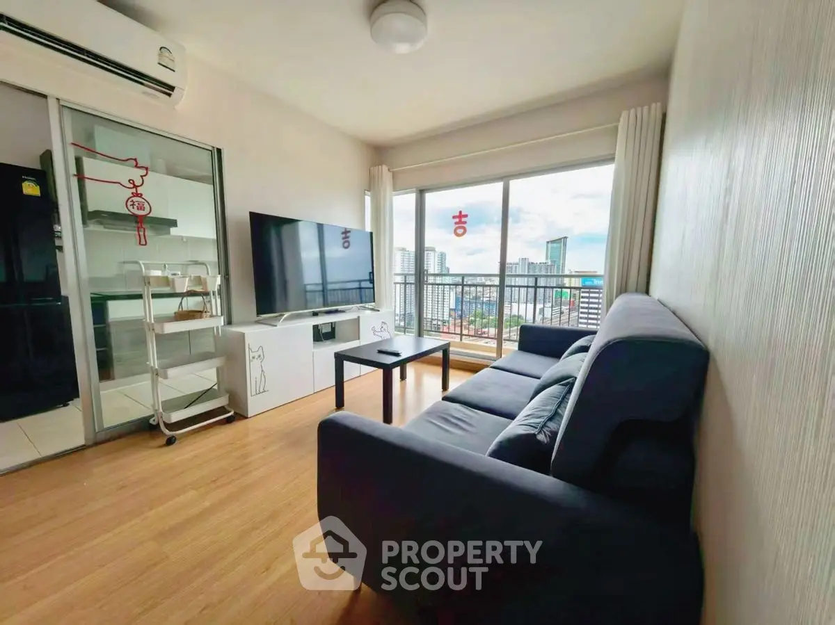 Modern living room with city view, featuring sleek furniture and large windows.