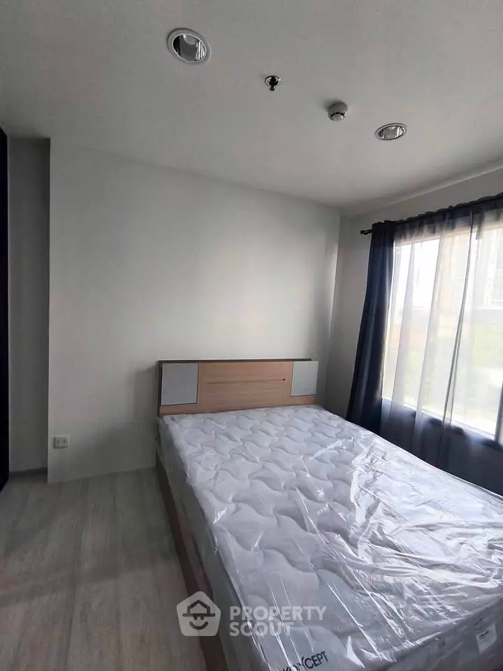 Modern bedroom with large window and natural light in a stylish apartment.