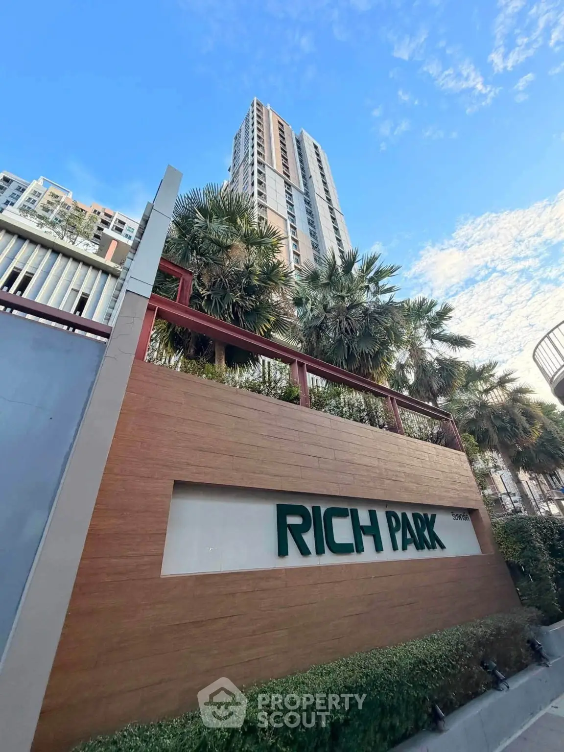 Modern high-rise building with lush greenery at Rich Park, showcasing urban living with nature.