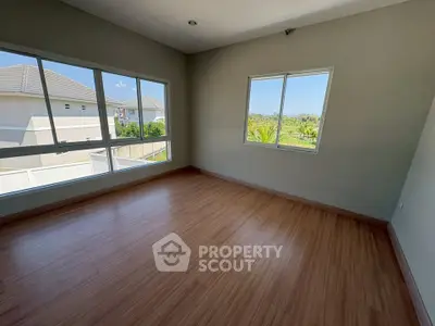 Spacious empty room with large windows and wooden flooring, perfect for customization.