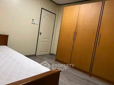 Cozy bedroom with wooden wardrobe and bed, perfect for minimalist living.