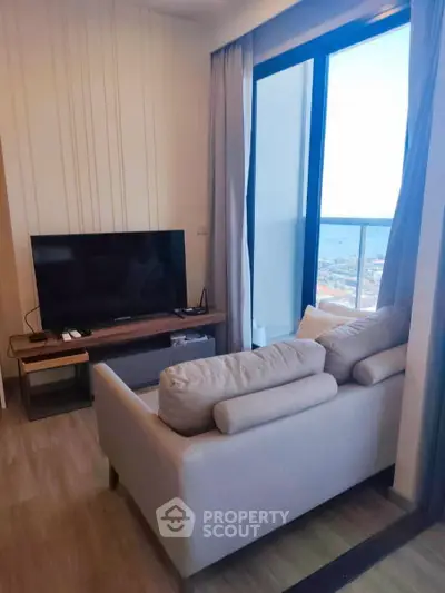 Modern living room with cozy sofa and large TV, featuring a stunning ocean view from the balcony.