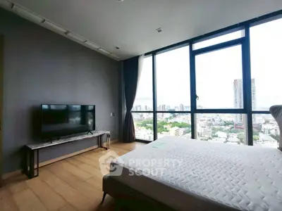 Spacious bedroom with large windows offering stunning city views and modern furnishings.