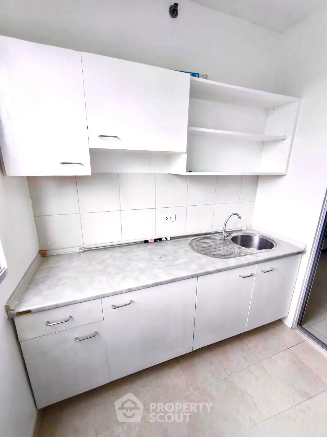 Compact kitchen with white cabinets and stainless steel sink, ideal for modern apartments.