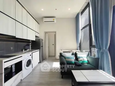 Modern living room with washing machine and large windows, featuring sleek furniture and natural light.