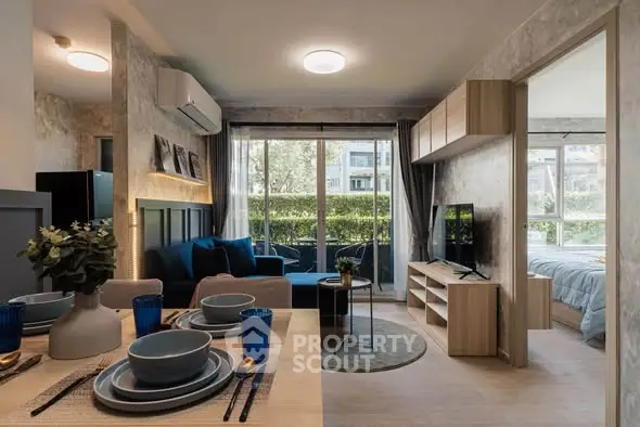 Modern open-plan living room with dining area and large windows overlooking greenery.