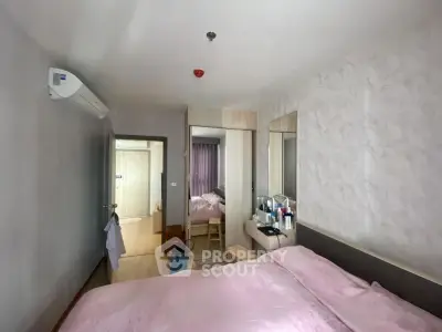 Cozy bedroom with modern decor and ample natural light, featuring a stylish mirrored wardrobe and air conditioning.