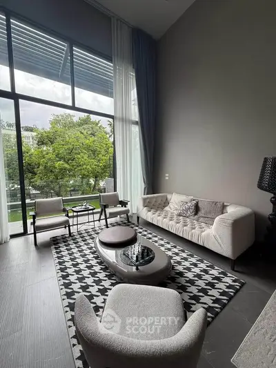 Luxurious living room with high ceilings and large windows overlooking greenery.