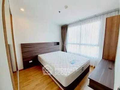 Spacious bedroom with large window and modern furnishings in a bright apartment.