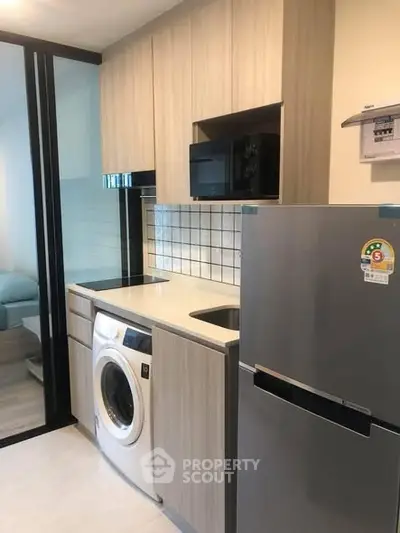 Modern kitchen with washing machine, fridge, and microwave in compact layout
