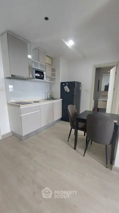 Modern kitchen with sleek cabinetry and dining area in a contemporary apartment.