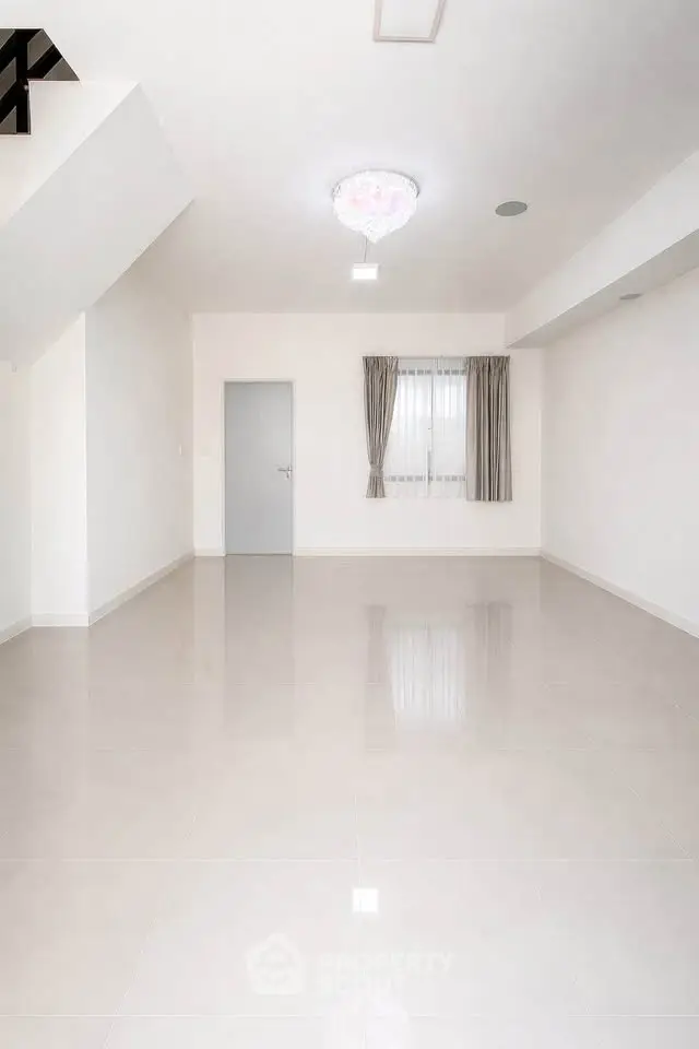 Spacious empty room with glossy tiled floor and elegant chandelier, ideal for customization.