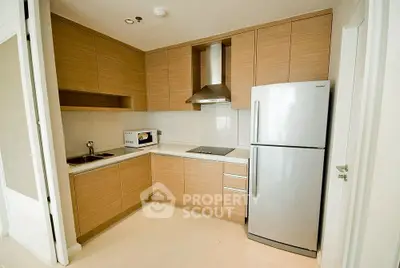 Modern kitchen with wooden cabinets and stainless steel appliances in a cozy apartment.