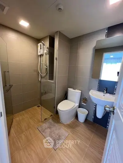 Modern bathroom with glass shower and sleek fixtures in contemporary home.