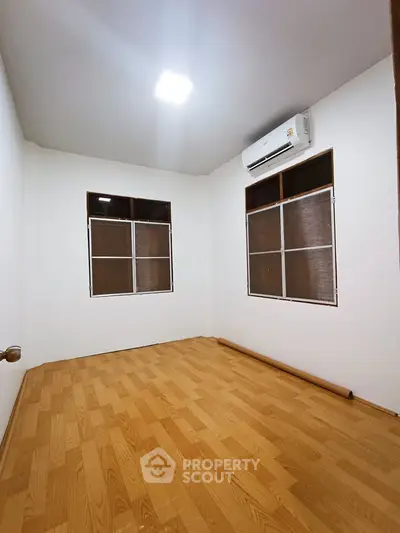 Cozy bedroom with wooden flooring and air conditioning unit, perfect for comfort and relaxation.
