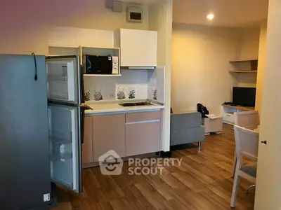 Modern open-layout kitchen and living area with wooden flooring and sleek appliances.