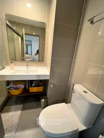 Modern bathroom with sleek fixtures and large mirror in contemporary apartment.