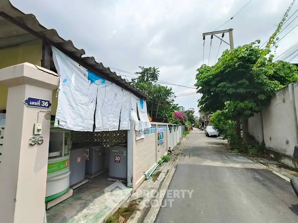 Charming residential alley with laundry area and lush greenery, perfect for tranquil living.